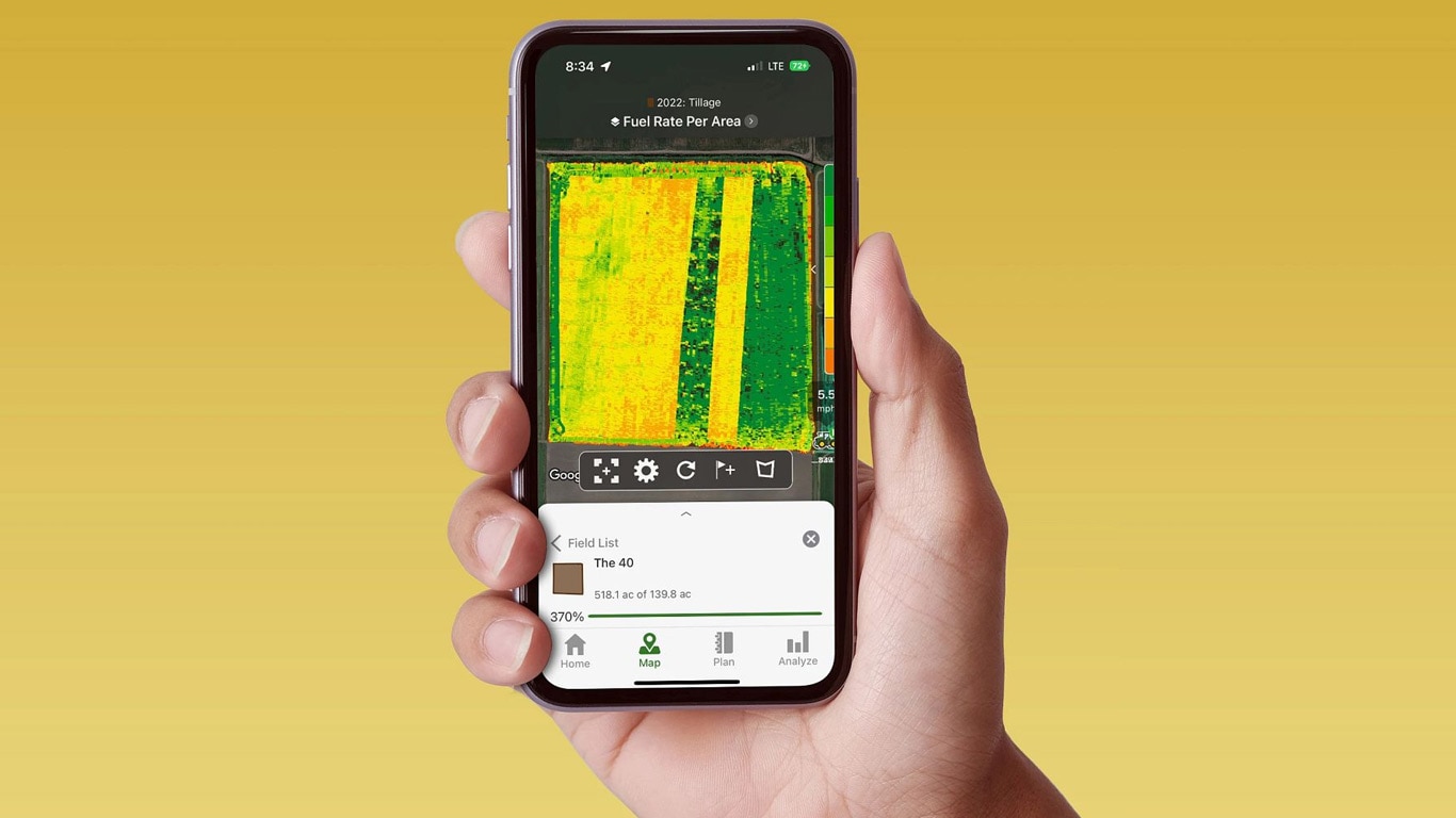 Hand met een smartphone met het John Deere Operations Center met gegevens over brandstofverbruik.