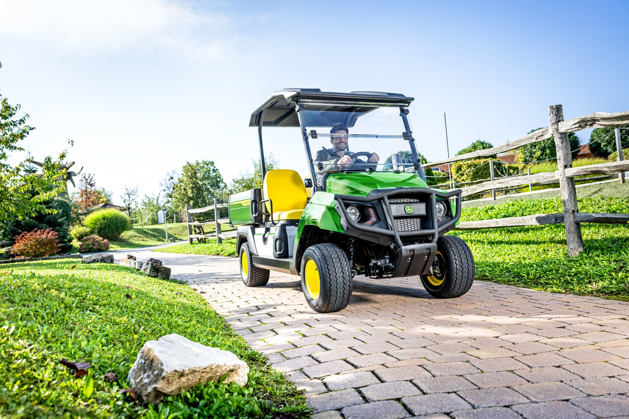 Universeel Gator GS-voertuig rijdend op een verharde weg in een aangelegd gebied Universeel Gator GS-voertuig rijdend op een verharde weg in een aangelegd gebied