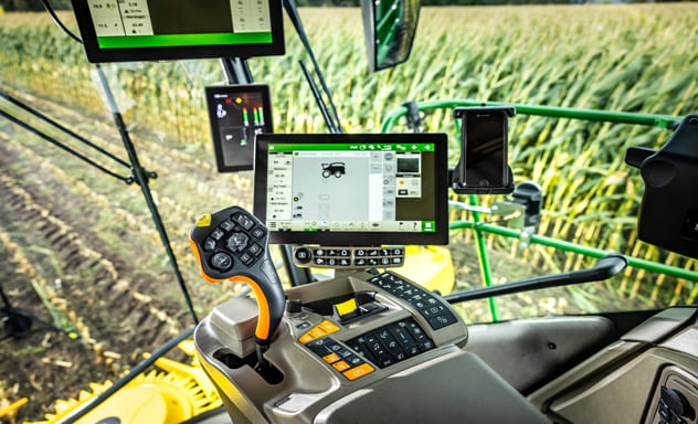 Zelfrijdende veldhakselaar F9 700 die een Joskin-aanhangwagen laadt, die wordt getrokken door een 6R-tractor van John Deere